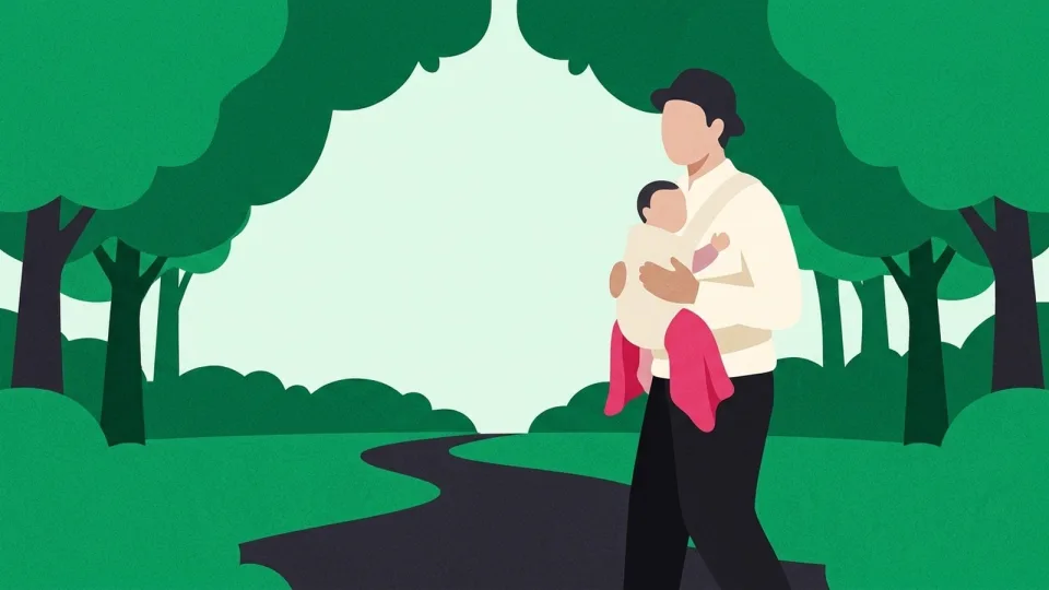 Father walking along a path at dusk with his baby in a front carrier