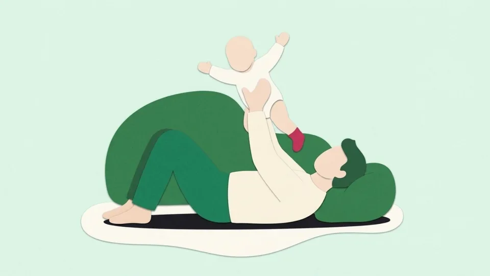 Father lying on a rug holding his delighted baby up in the air