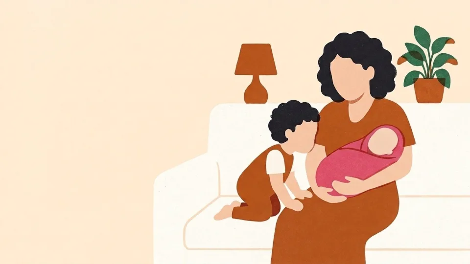 Mother on a sofa holding a newborn while her preschooler kneels beside her and leans in to look at the baby